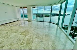 Expansive living area featuring floor-to-ceiling glass walls, large-format stone tile flooring, and integrated built-in cabinetry