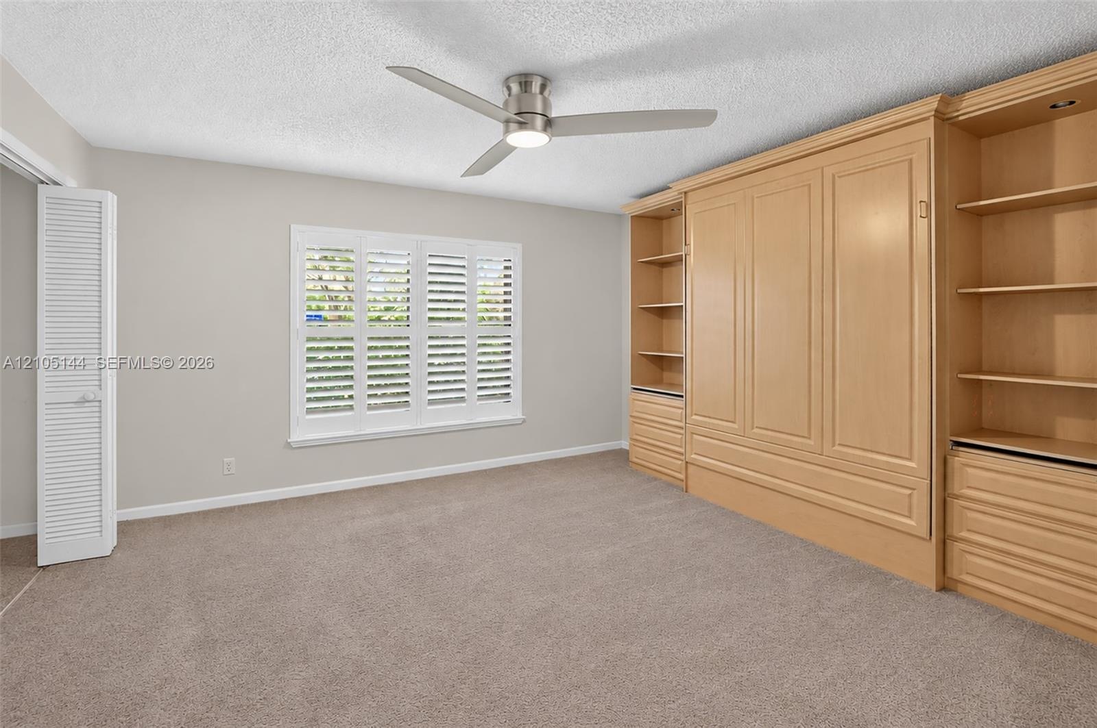 (FAN VIRTUALLY STAGED AS SIMILAR PIECE WILL BE INSTALLED) Custom light-toned built-in cabinetry, window with plantation shutters, ceiling fan with int