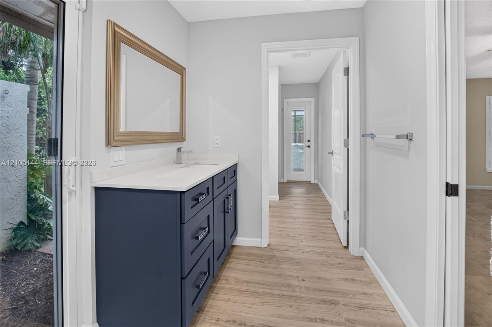 Dark-toned vanity with a solid-surface countertop and integrated sink, complemented by wood-finish flooring and a wall-mounted towel bar