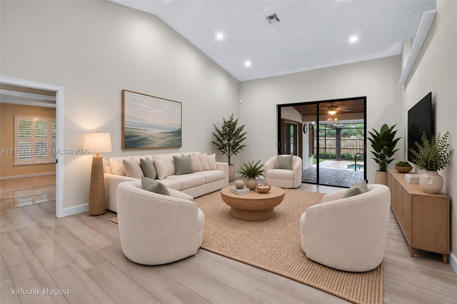 Living area featuring a vaulted ceiling, wood-finish flooring, recessed lighting, and large sliding glass doors leading to the exterior