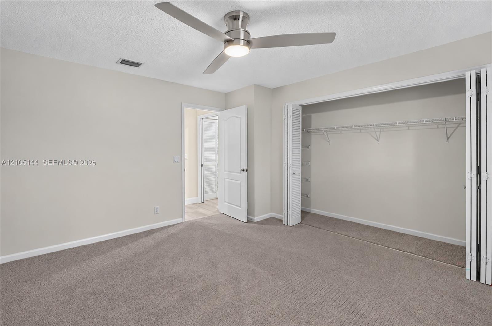 (FAN VIRTUALLY STAGED AS SIMILAR PIECE WILL BE INSTALLED) Neutral-toned interior space featuring neutral wall-to-wall carpeting, a satin-nickel finish