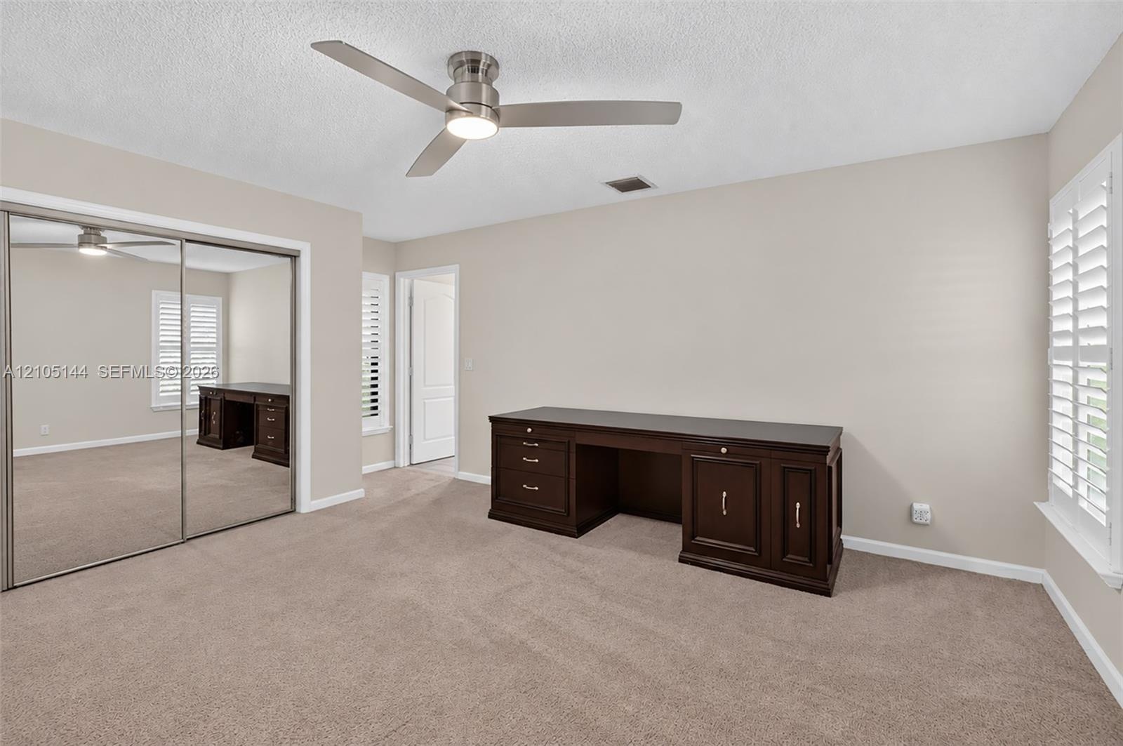 (FAN VIRTUALLY STAGED AS SIMILAR PIECE WILL BE INSTALLED) Bedroom featuring neutral carpet, mirrored sliding closet doors, a ceiling fan with integrat