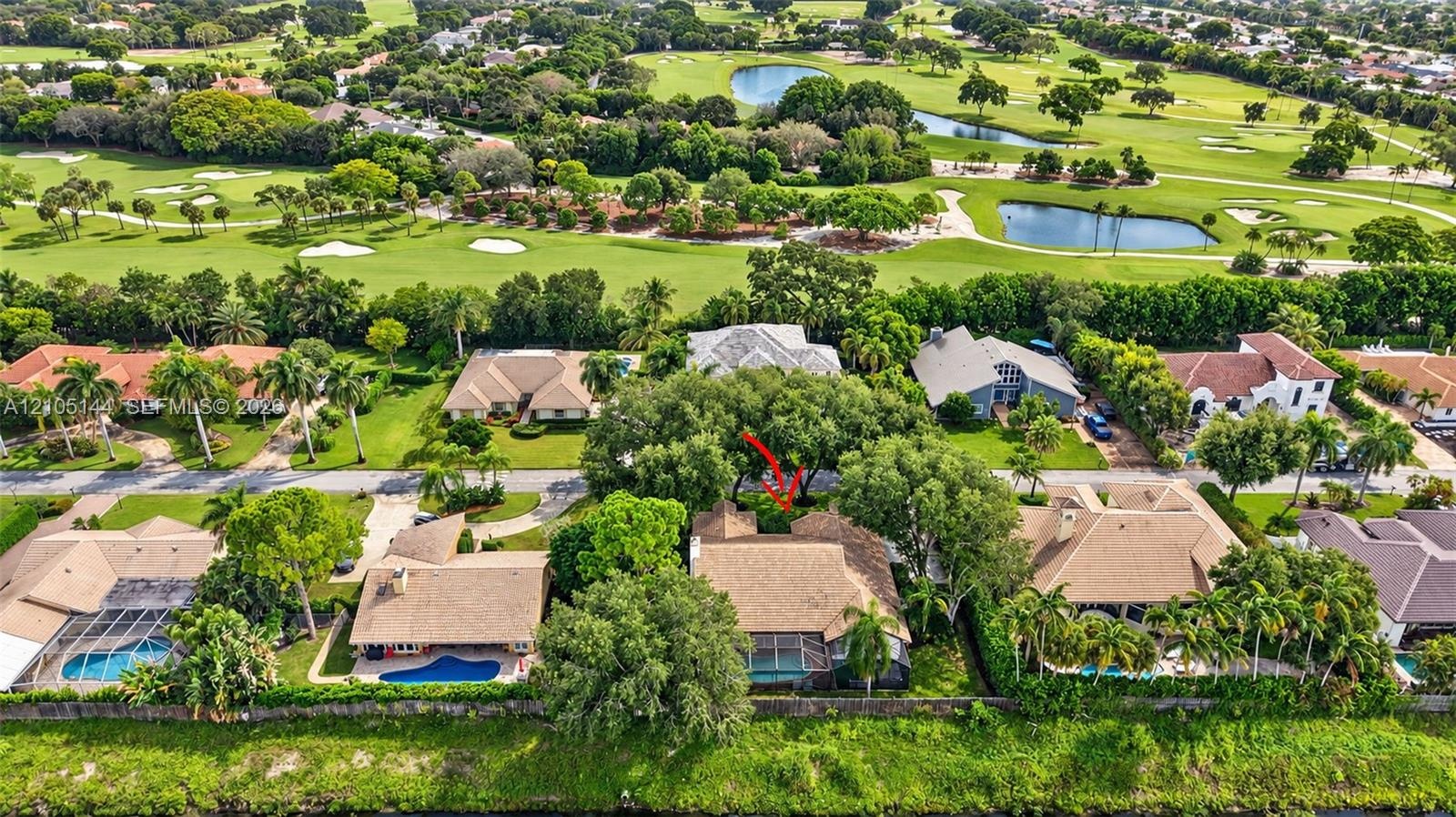 Aerial perspective showcasing a residential property with a shingle roof and a screened-in lanai, situated on a golf course lot featuring mature trees