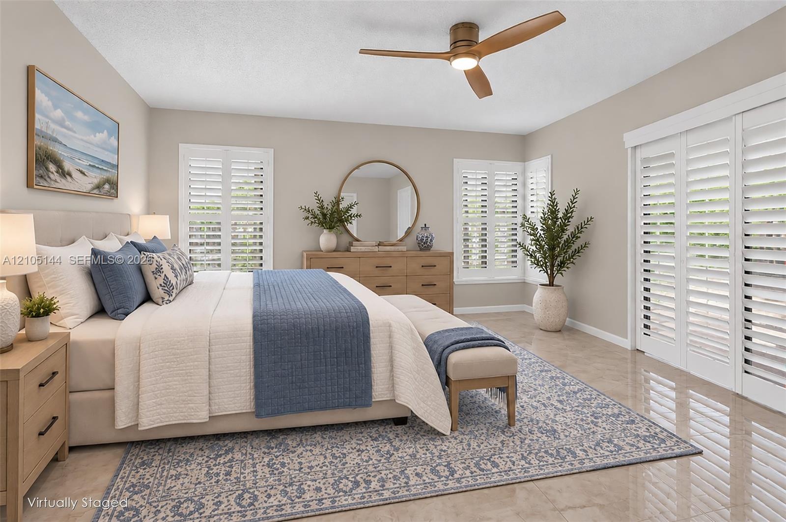 Neutral-toned bedroom featuring large-format tile flooring, plantation shutters, and a modern three-blade ceiling fan with integrated lighting
