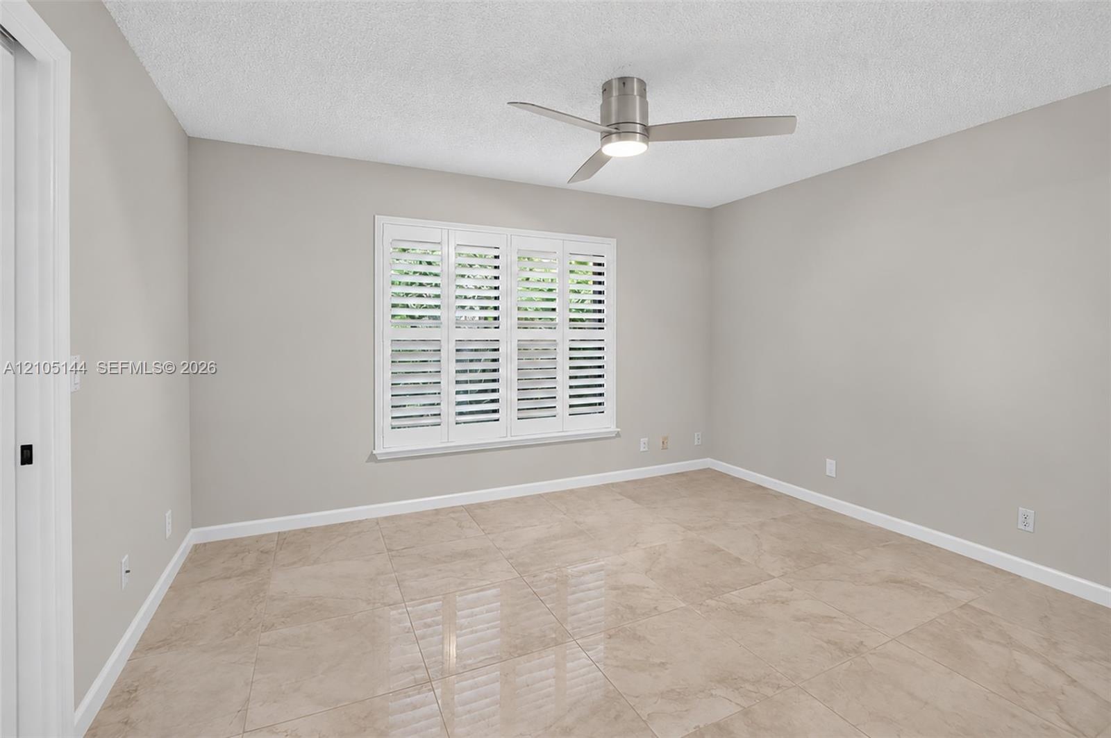 (FAN VIRTUALLY STAGED AS SIMILAR PIECE WILL BE INSTALLED)Neutral interior featuring large-format tile flooring, crisp neutral wall paint, white planta