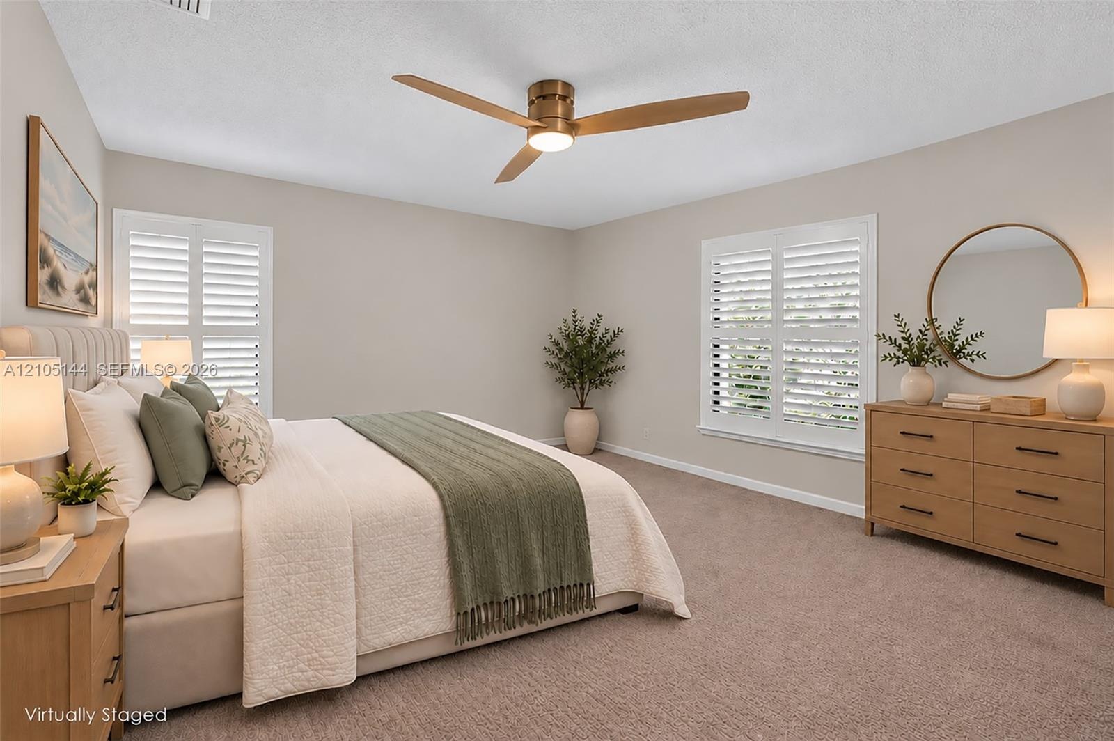 Neutral interior walls, wall-to-wall carpeting, dual windows with white plantation shutters, and a central ceiling fan with integrated lighting