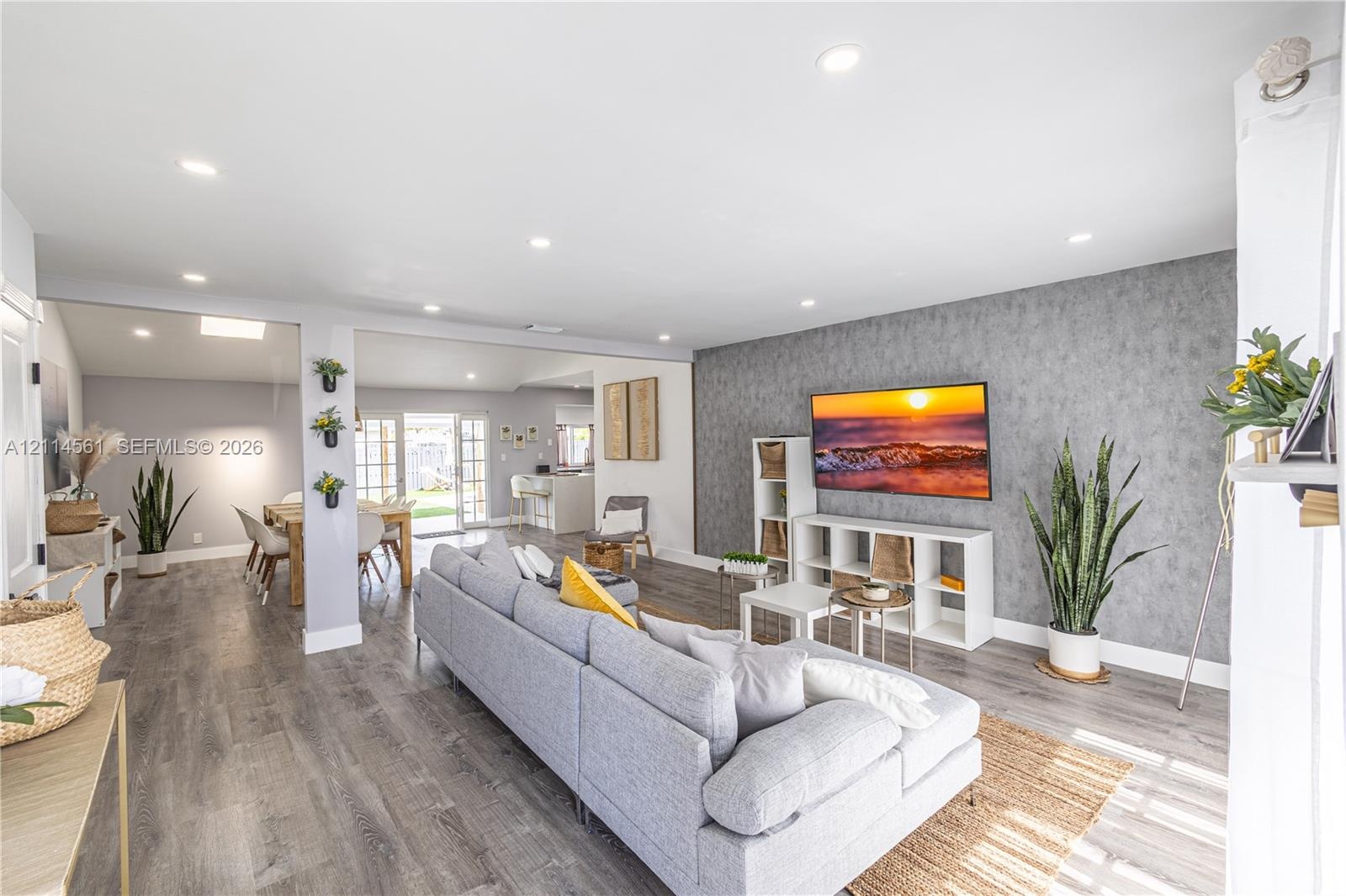 Open-concept living space featuring wood-finish flooring, recessed lighting, and a textured accent wall