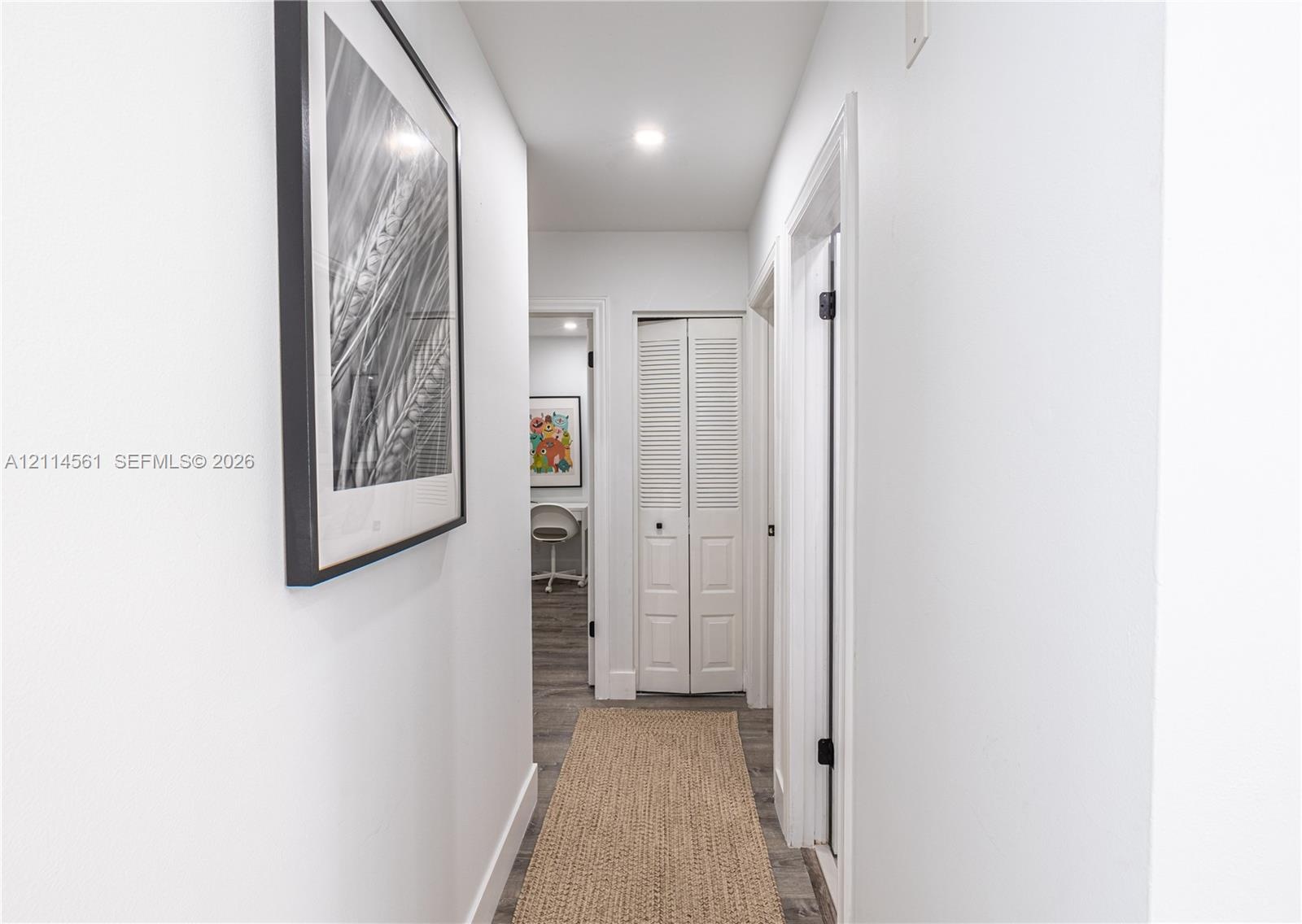 Hallway featuring recessed ceiling lighting, louvered bi-fold closet doors, and wood-finish flooring