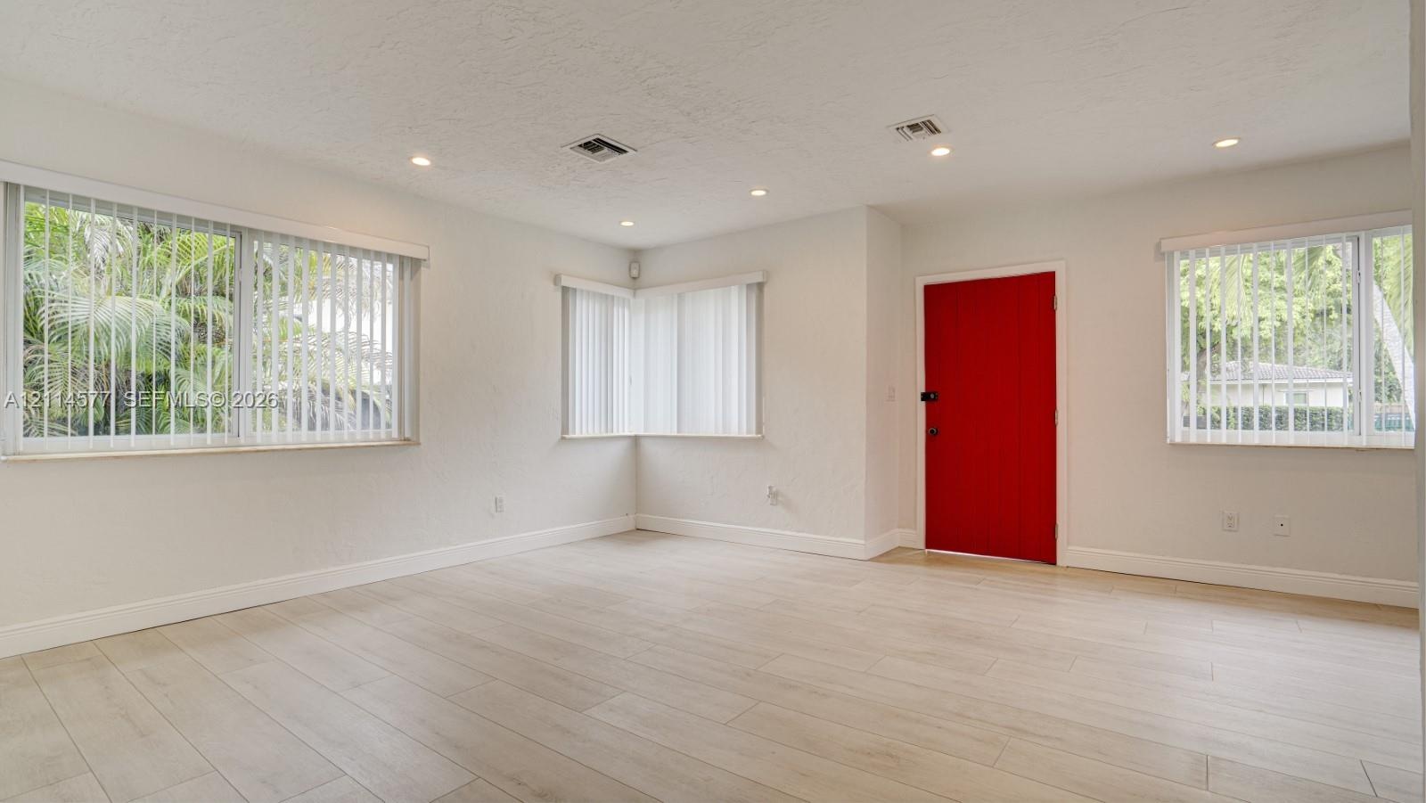 Neutral walls paired with light-toned wood-finish flooring, recessed lighting, and vertical window blinds