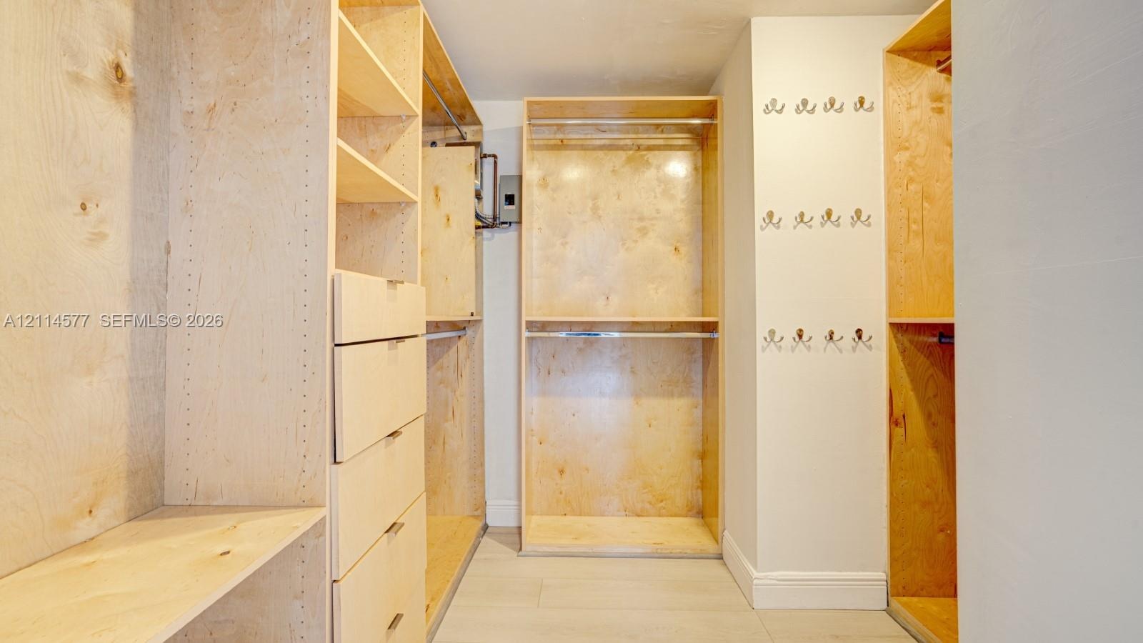 Custom wood-finish storage cabinetry featuring integrated drawer banks, adjustable shelving, tiered clothing rods, and wall-mounted hardware