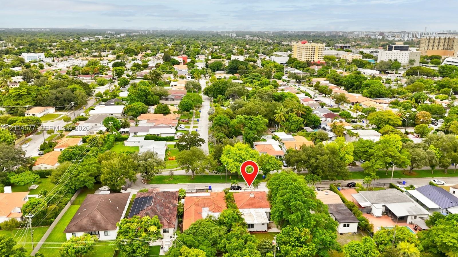 Aerial perspective of a residential property featuring a tiled roof, mature canopy trees, and established landscaping