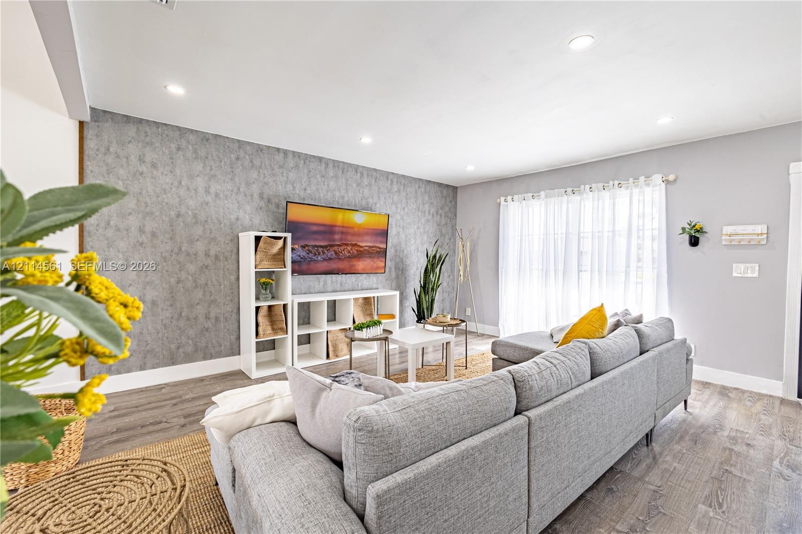 Living area featuring wood-finish flooring, recessed lighting, and a textured accent wall