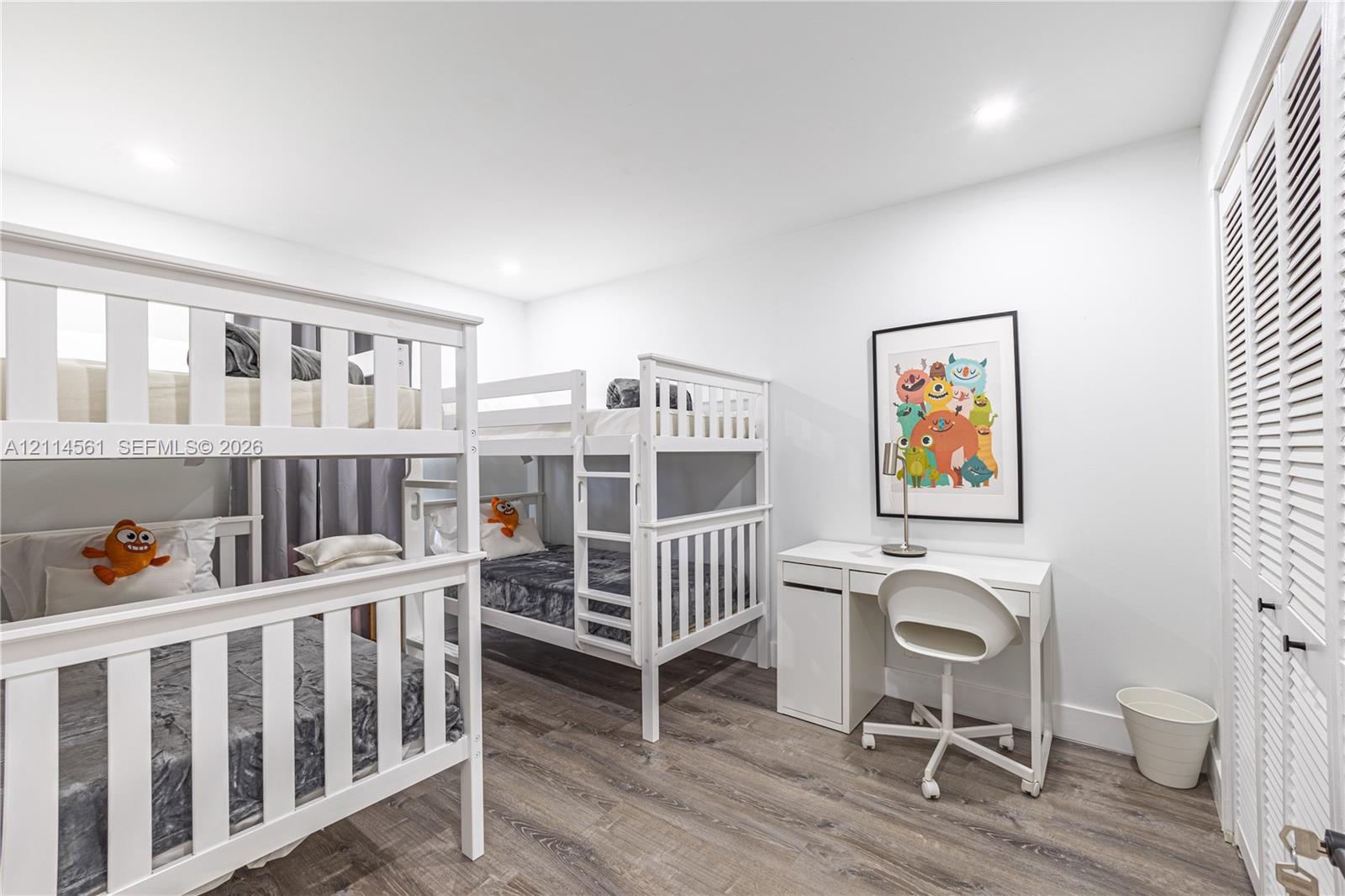Wood-finish flooring, recessed lighting, and white louvered closet doors