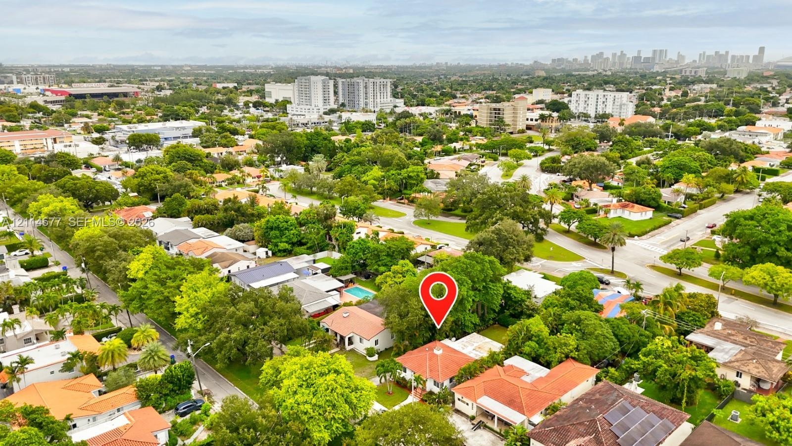 Aerial view featuring a residential property with a multi-level tile roof, surrounding mature landscaping, and an established street grid