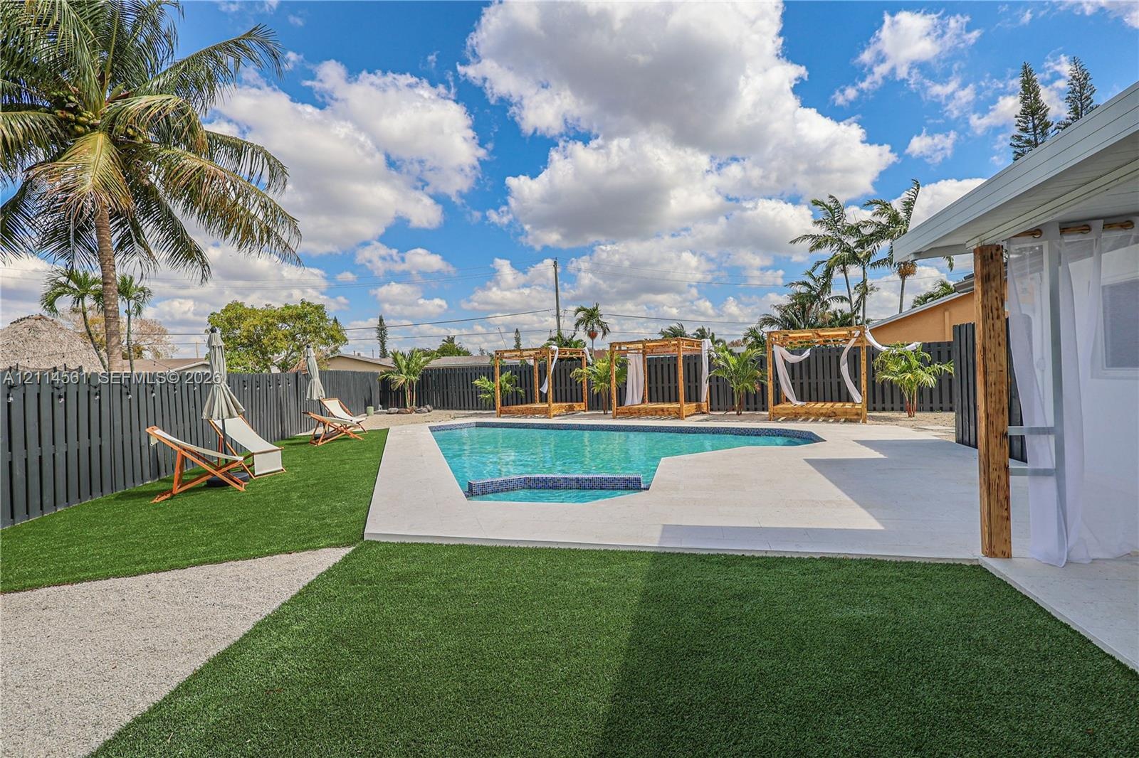 Outdoor space featuring an in-ground swimming pool, concrete pool deck, synthetic turf, and perimeter privacy fencing