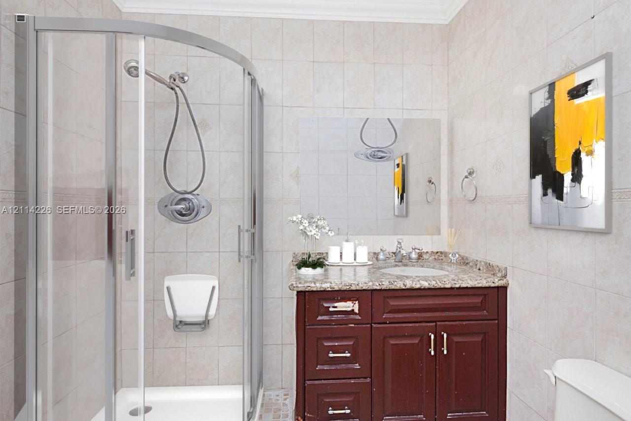 Curved glass shower enclosure with a handheld shower head and wall-mounted seat, complemented by a dark wood vanity, stone-finish countertop, and inte