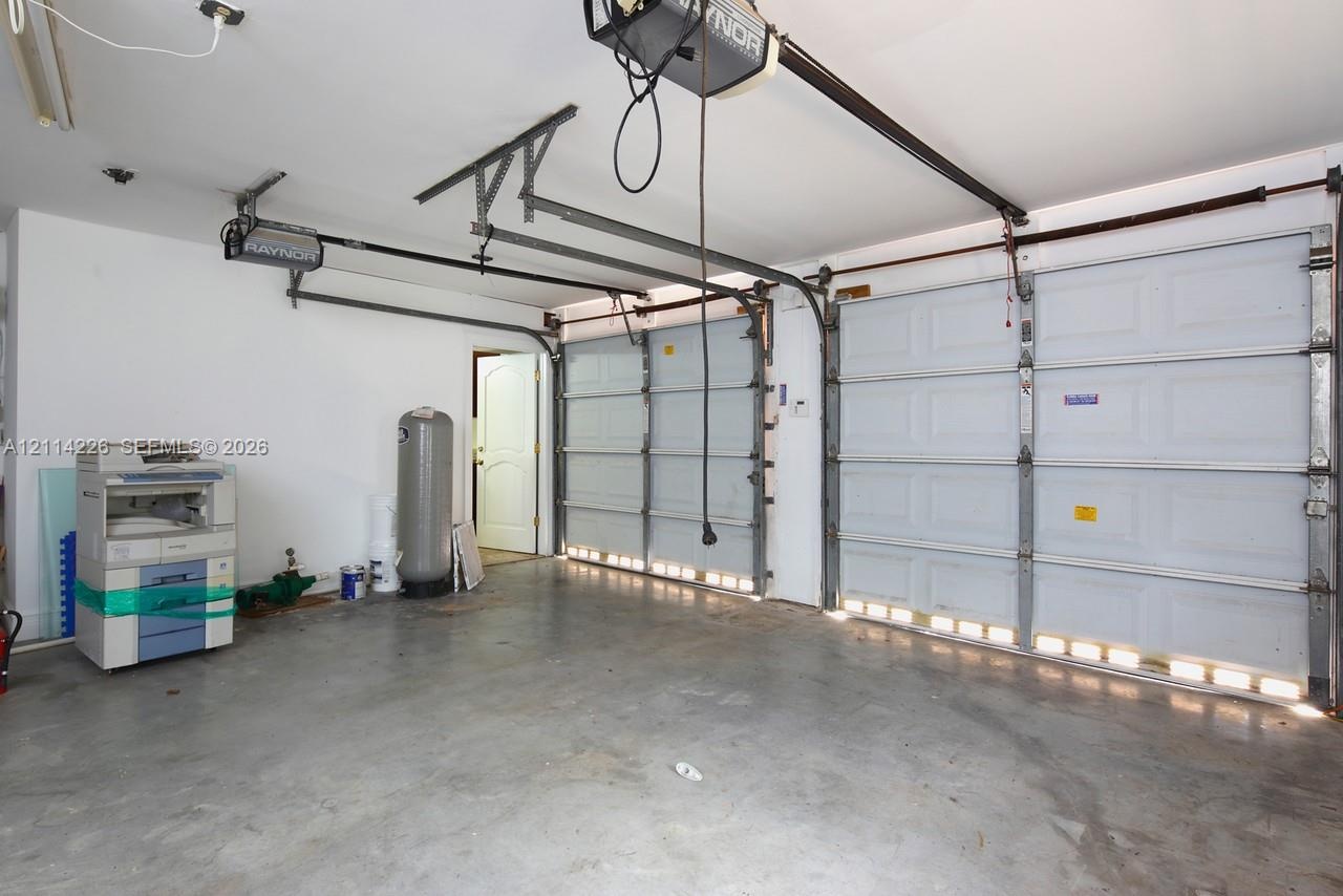 Multi-car garage featuring dual overhead metal doors, concrete flooring, and an integrated automated door opener system