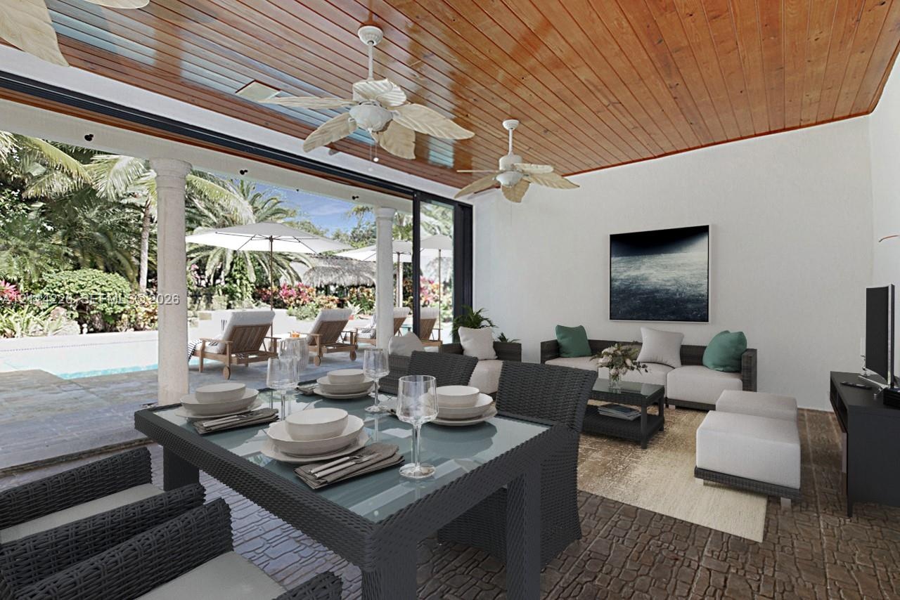 Covered outdoor living space featuring a polished wood-plank ceiling, dual ceiling fans, stone flooring, and structural columns