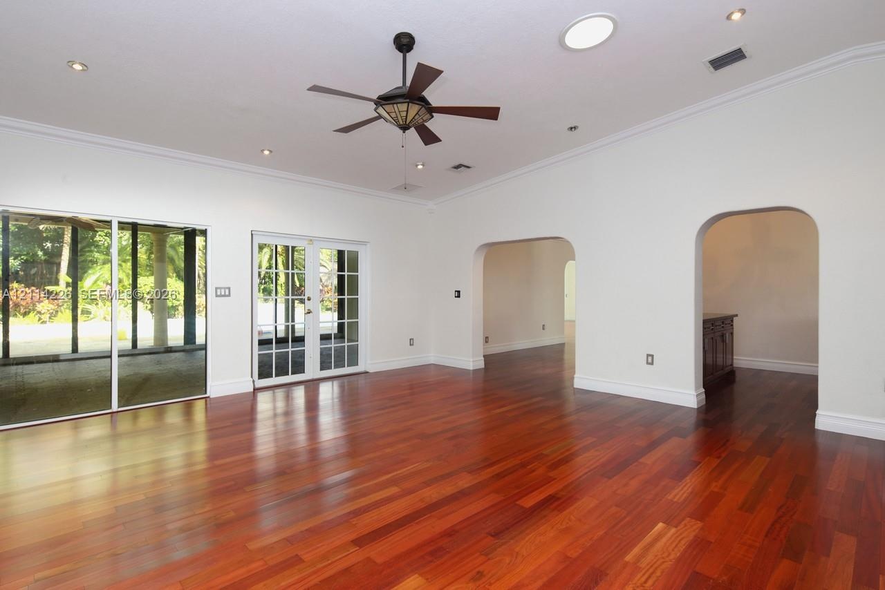 High-ceiling interior featuring wood-finish flooring, arched doorways, a ceiling fan, recessed lighting, and a glass-paned sliding door