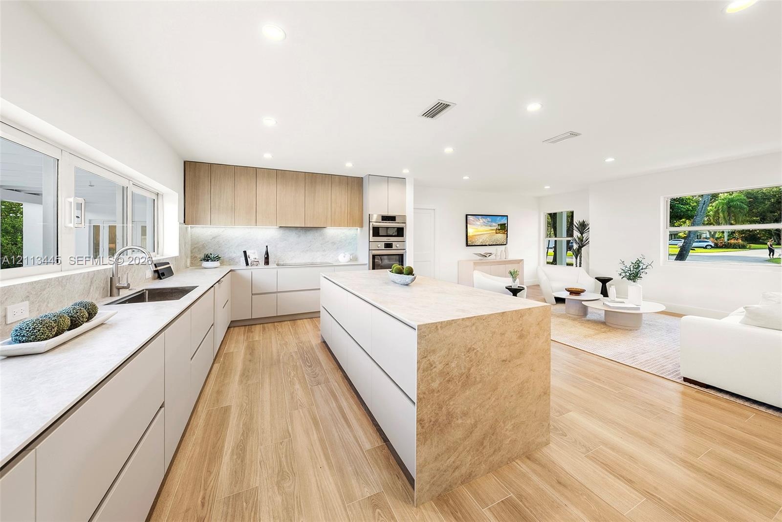 Kitchen featuring flat-panel cabinetry, a central island with stone-finish surfaces, integrated stainless steel double wall ovens, recessed lighting, 