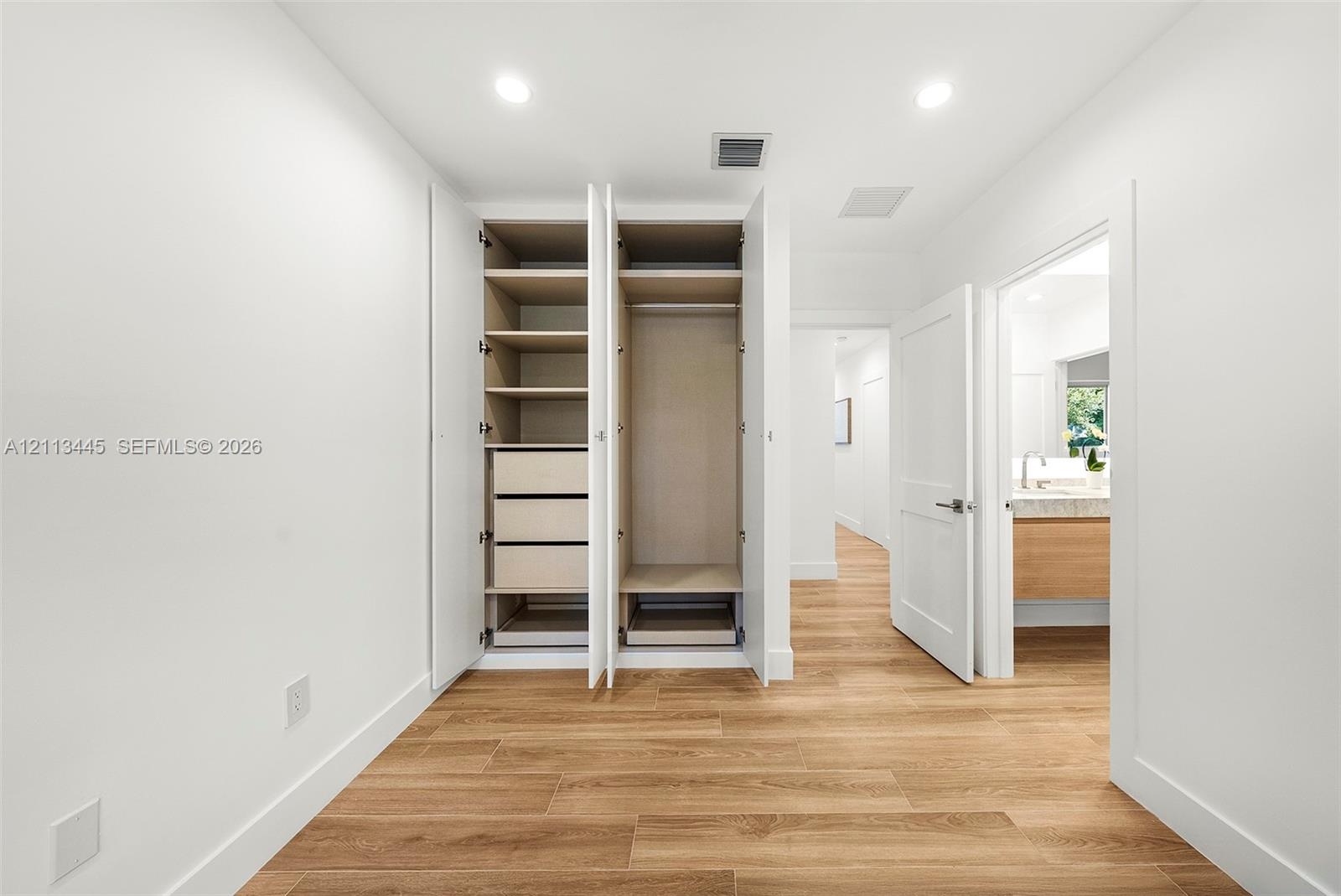 Built-in cabinetry featuring adjustable shelving and integrated drawer storage, recessed lighting, and wood-finish flooring