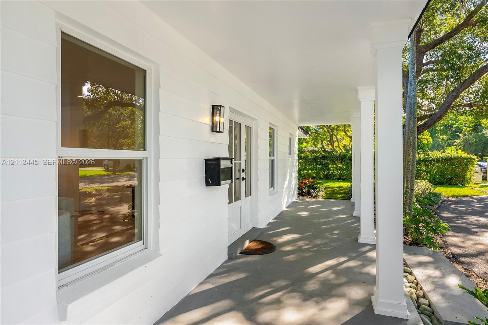 Covered front porch featuring smooth-finish ceiling, square structural columns, horizontal lap siding, wall-mounted exterior lighting, and double-entr