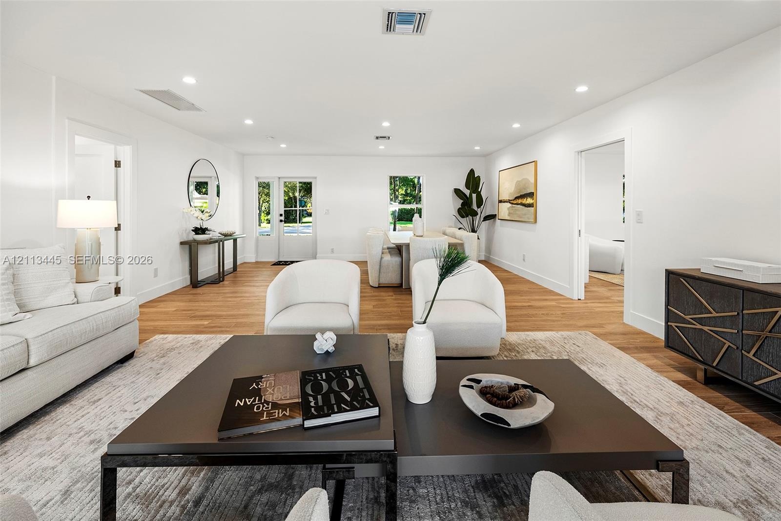 Open-concept interior featuring wood-finish flooring, recessed lighting, and a glass-paneled entry door