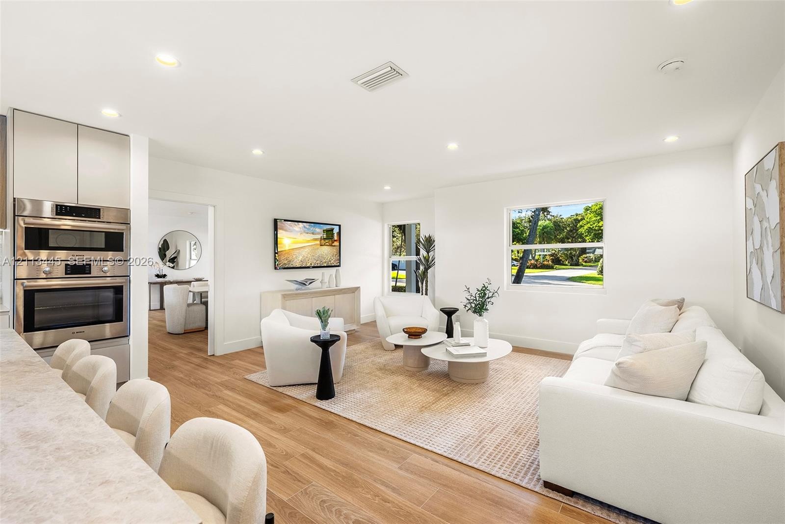Open-concept interior featuring wood-finish flooring, recessed lighting, and a built-in stainless steel double wall oven