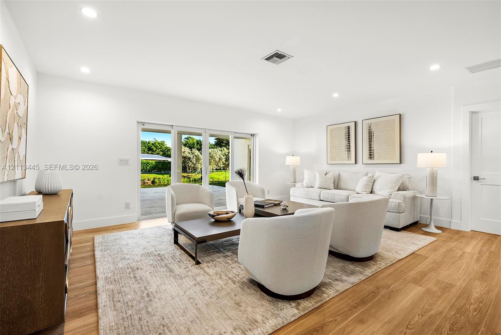 Living area featuring wood-finish flooring, recessed lighting, and large sliding glass doors providing outdoor access