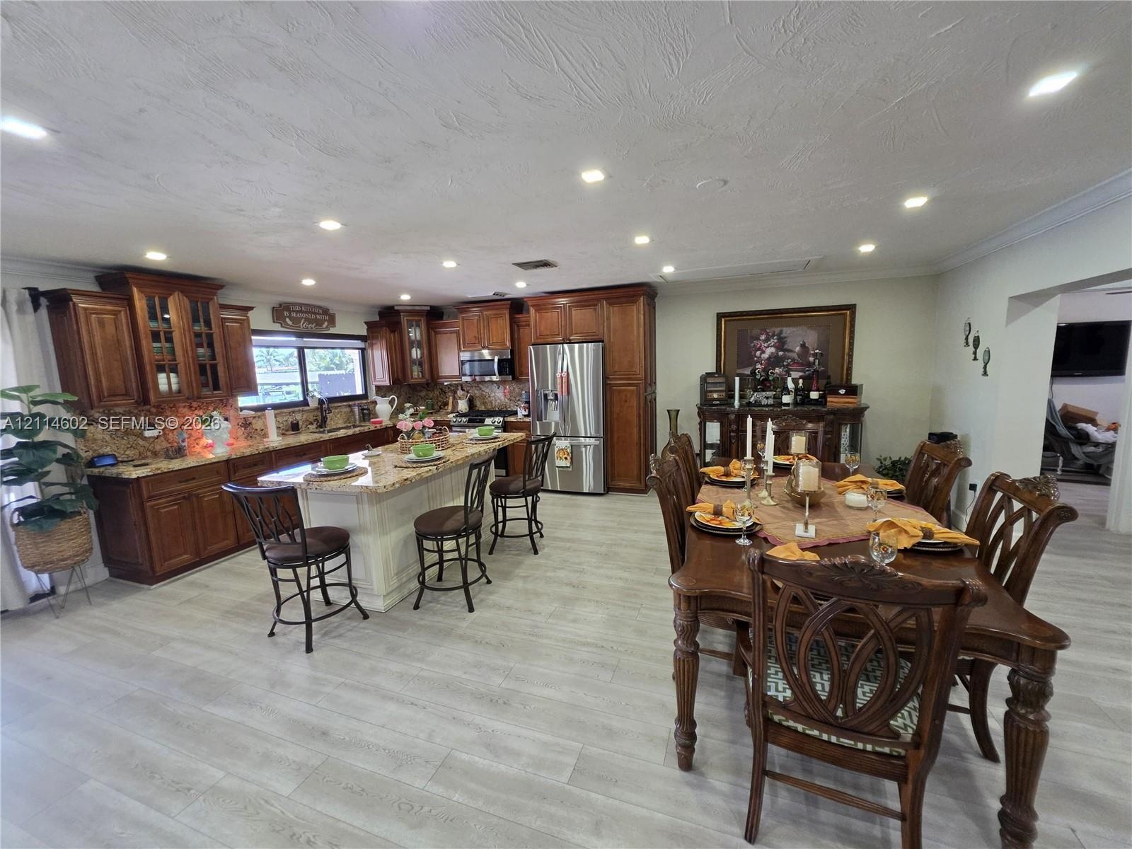 Kitchen featuring stained wood cabinetry, stone countertops, a central island, recessed lighting, and wood-finish flooring