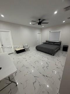 Large-format tile flooring with a veined pattern, recessed ceiling lighting, and a central ceiling fan