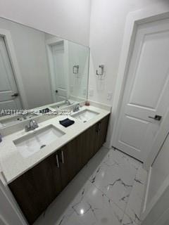 Double-sink vanity featuring dark wood-finish cabinetry, light-toned stone-finish countertop, undermount sinks, and polished chrome fixtures, compleme
