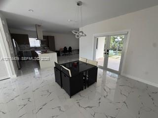 Polished stone-finish tile flooring, kitchen island with built-in cabinetry, stainless steel range hood, recessed lighting, and double glass pane door