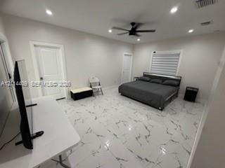 Spacious room featuring light-toned large-format tile flooring with veining, recessed lighting, a modern ceiling fan, and paneled doors