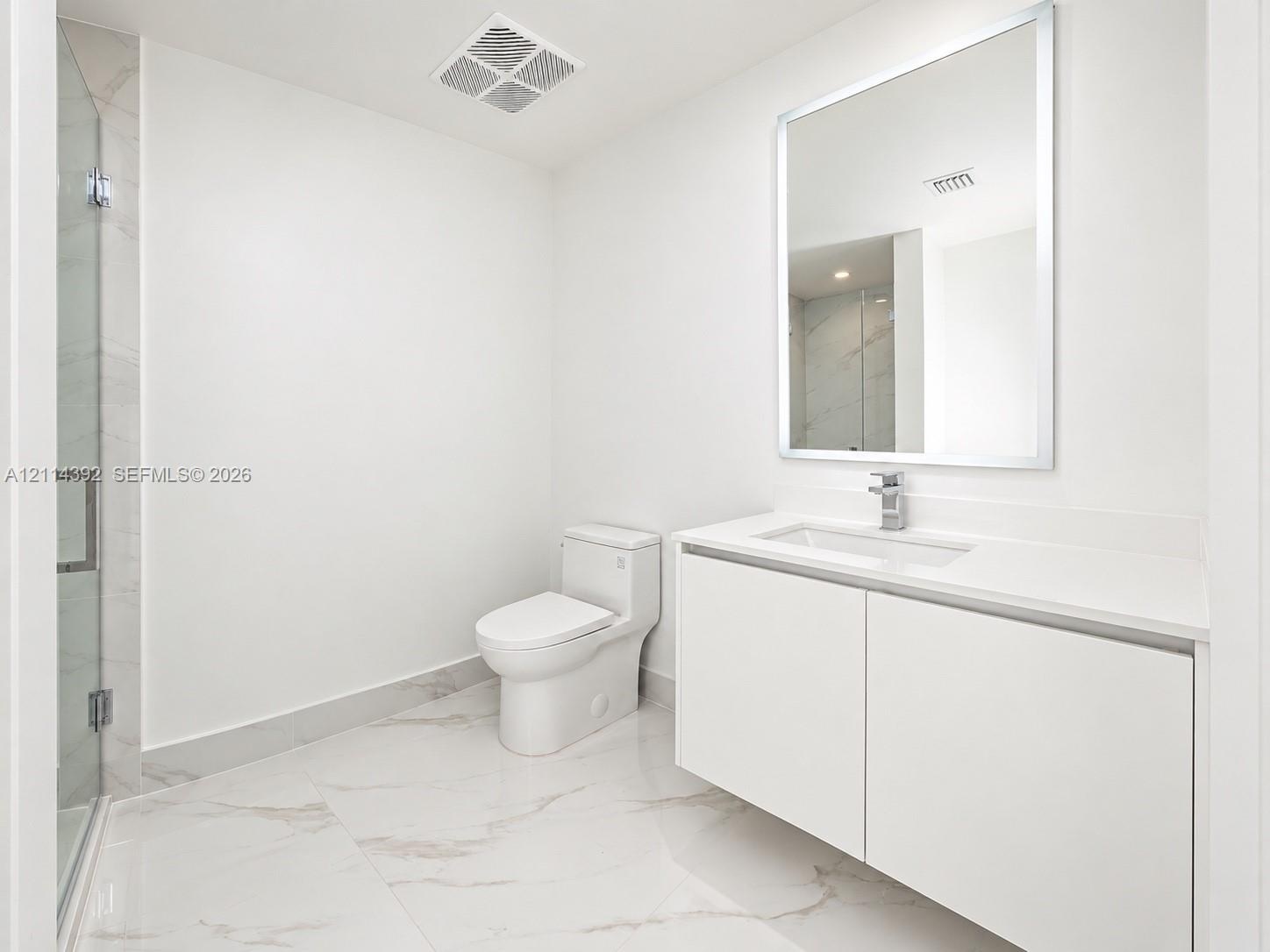 Modern bathroom featuring a floating vanity with a seamless countertop, rectangular sink, polished-edge mirror, and floor-to-ceiling tiled shower with