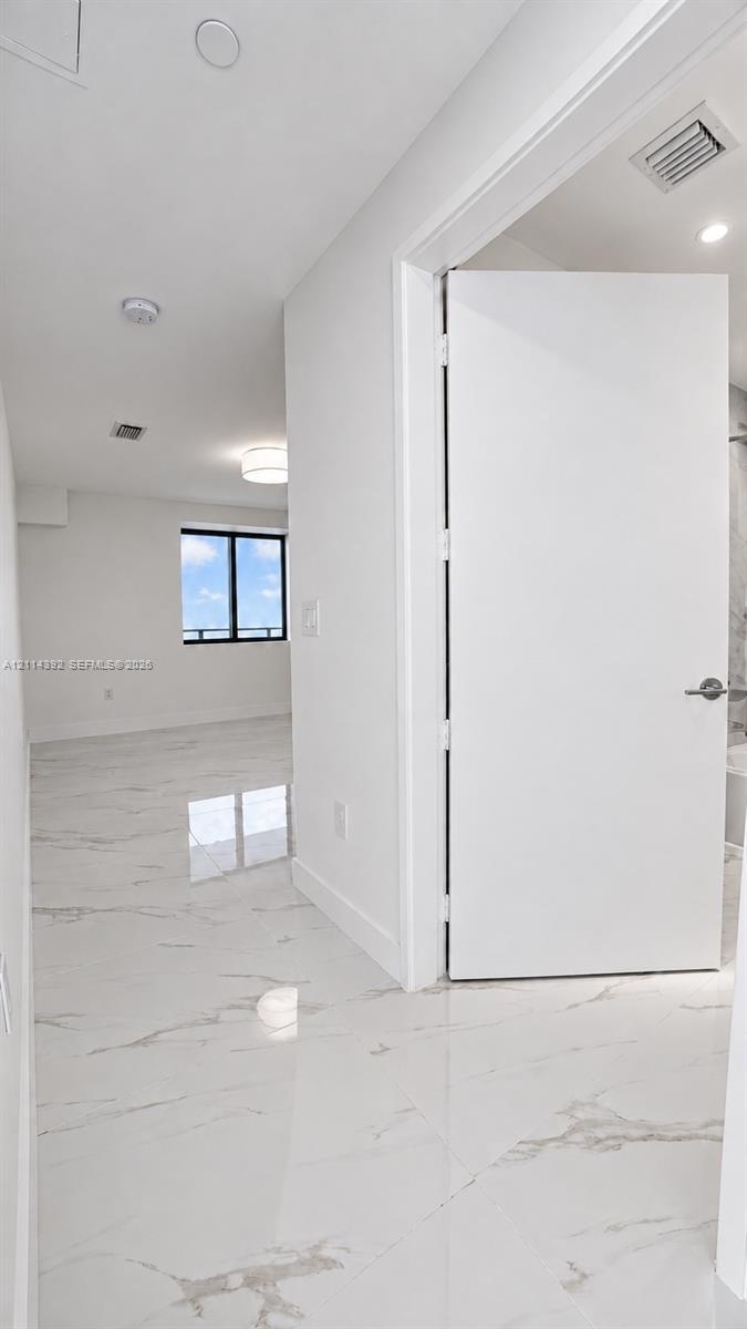 Large-format stone-finish tile flooring, minimalist solid-core interior door, and recessed lighting
