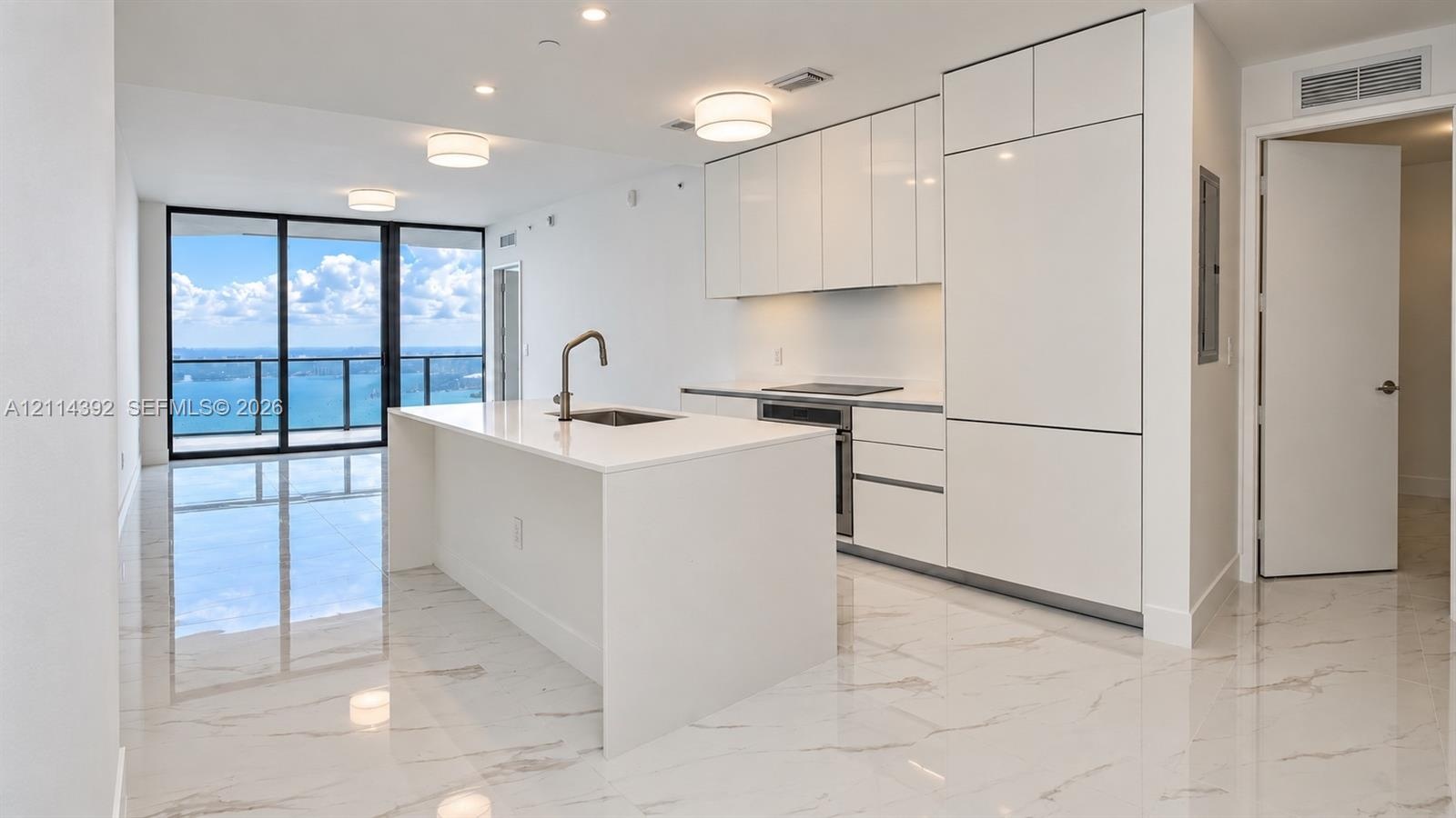 Modern kitchen featuring white flat-panel cabinetry, integrated appliances, a central island with a quartz countertop, and large-format porcelain tile