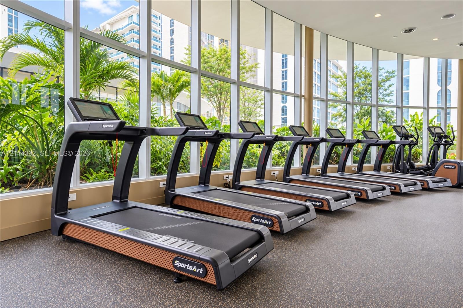 Fitness center featuring floor-to-ceiling windows, rubberized flooring, and professional-grade cardio equipment