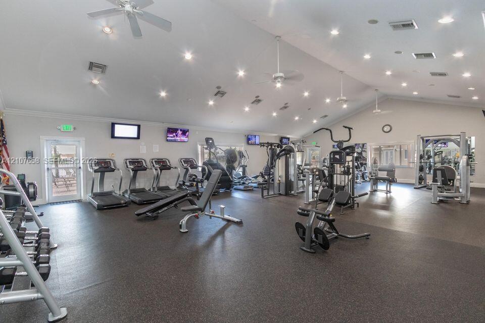 Fitness center featuring vaulted ceilings, recessed lighting, multiple ceiling fans, and impact-resistant rubber flooring