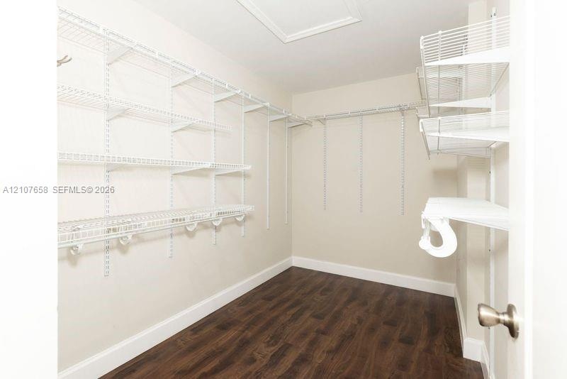 Walk-in storage space featuring wood-finish flooring and tiered white wire shelving units