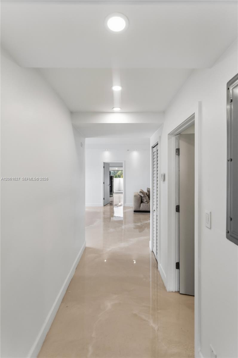 Hallway featuring polished concrete flooring, recessed lighting, and louvered closet doors