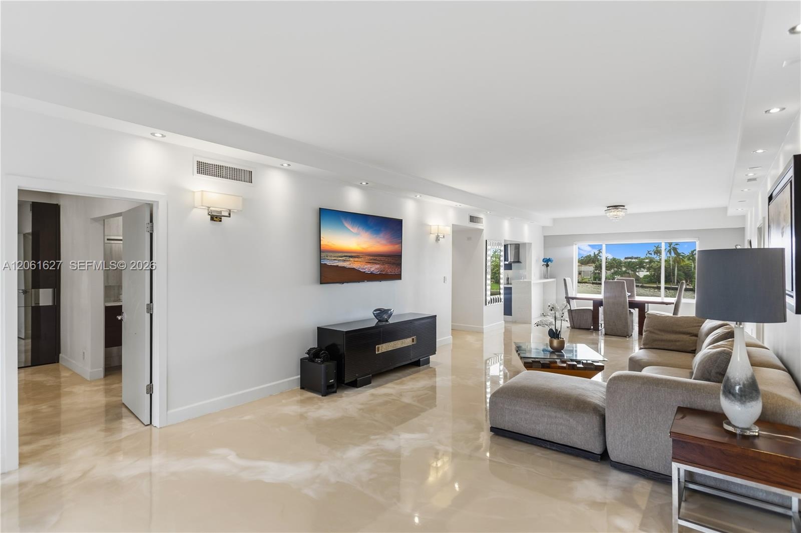 Polished stone flooring, recessed lighting, wall-mounted sconces, and large windows with outdoor scenery