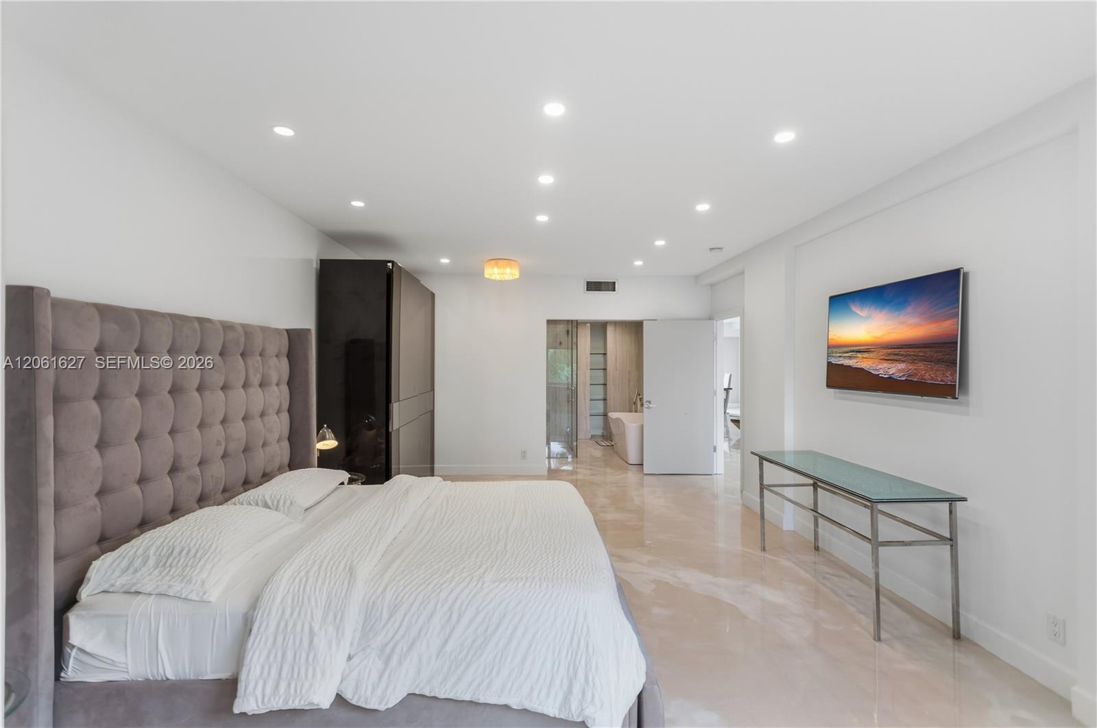Spacious room featuring polished stone flooring, recessed ceiling lighting, a dark finish built-in wardrobe, and a white architectural door