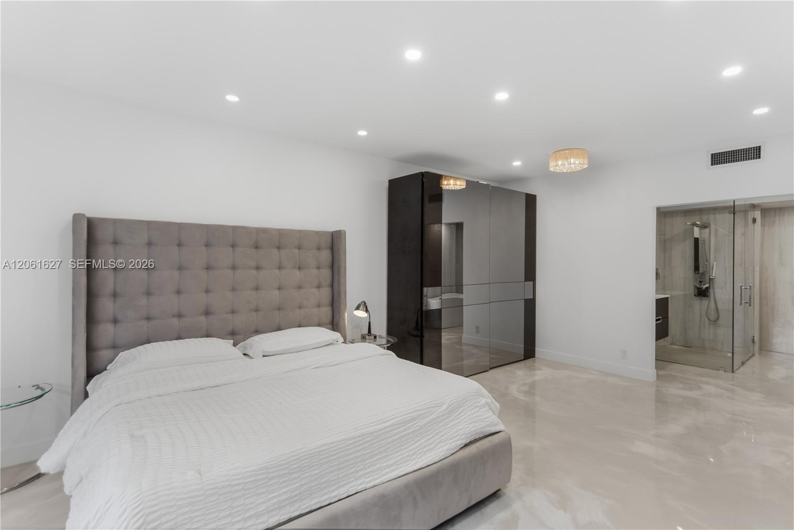 Polished stone flooring, recessed ceiling lighting, built-in floor-to-ceiling cabinetry with mirrored panels, and glass-enclosed shower stall