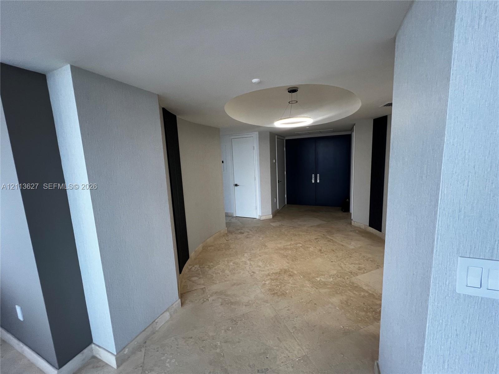 Interior space featuring large-format natural stone tile flooring, a recessed circular ceiling cove, circular LED flush-mount lighting, and solid-core