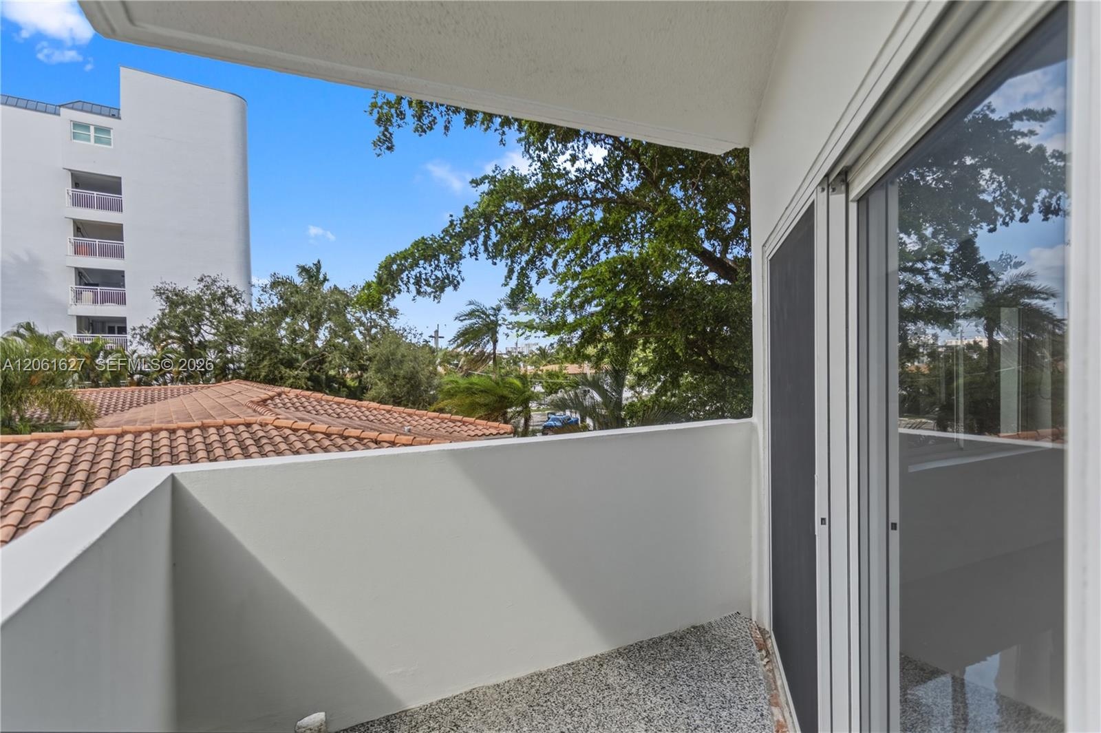 Covered balcony with a textured concrete floor and sliding glass door access