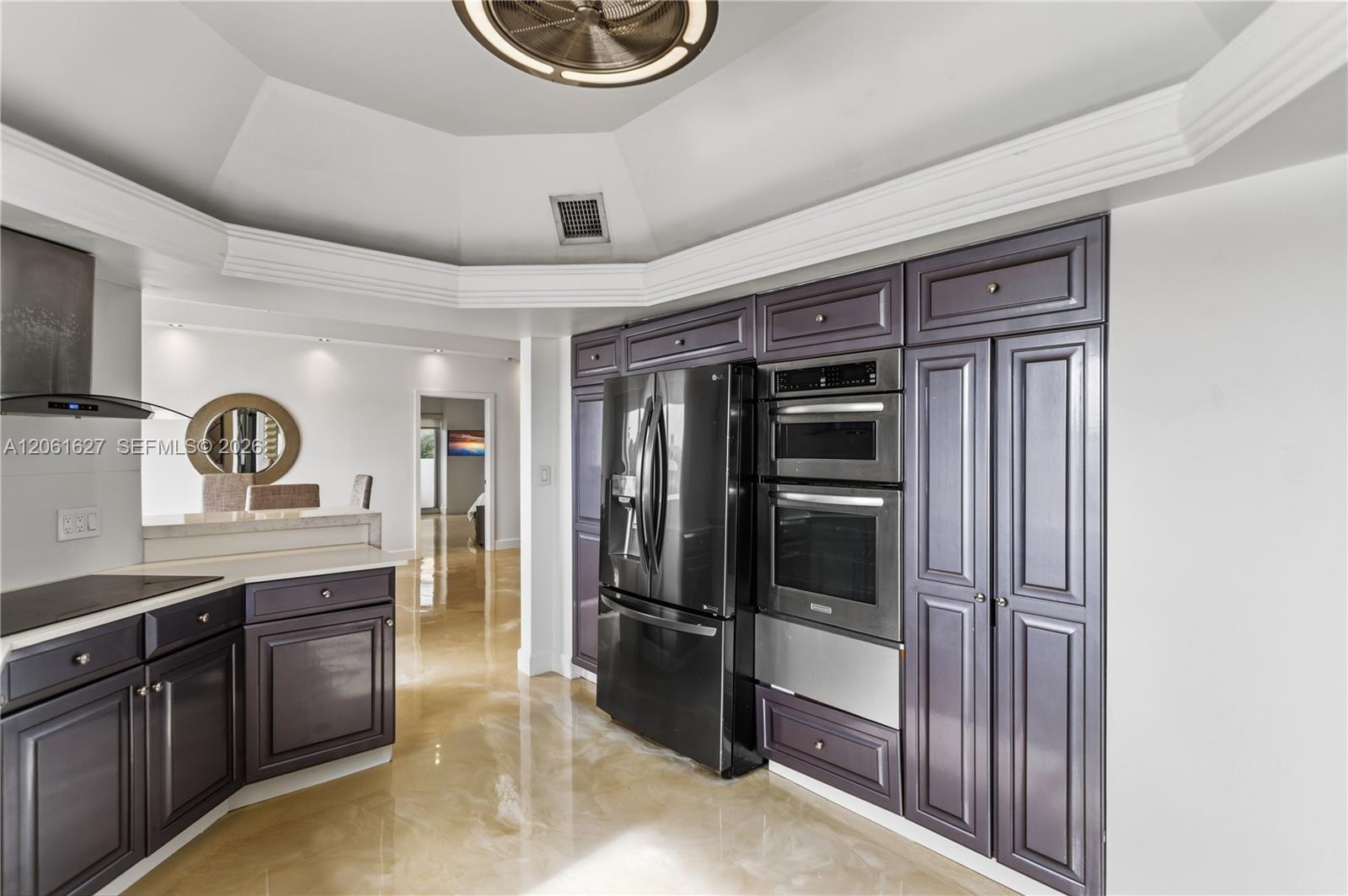 Kitchen featuring custom dark-toned cabinetry, stainless steel double wall oven, integrated microwave, built-in refrigerator, and a tray ceiling