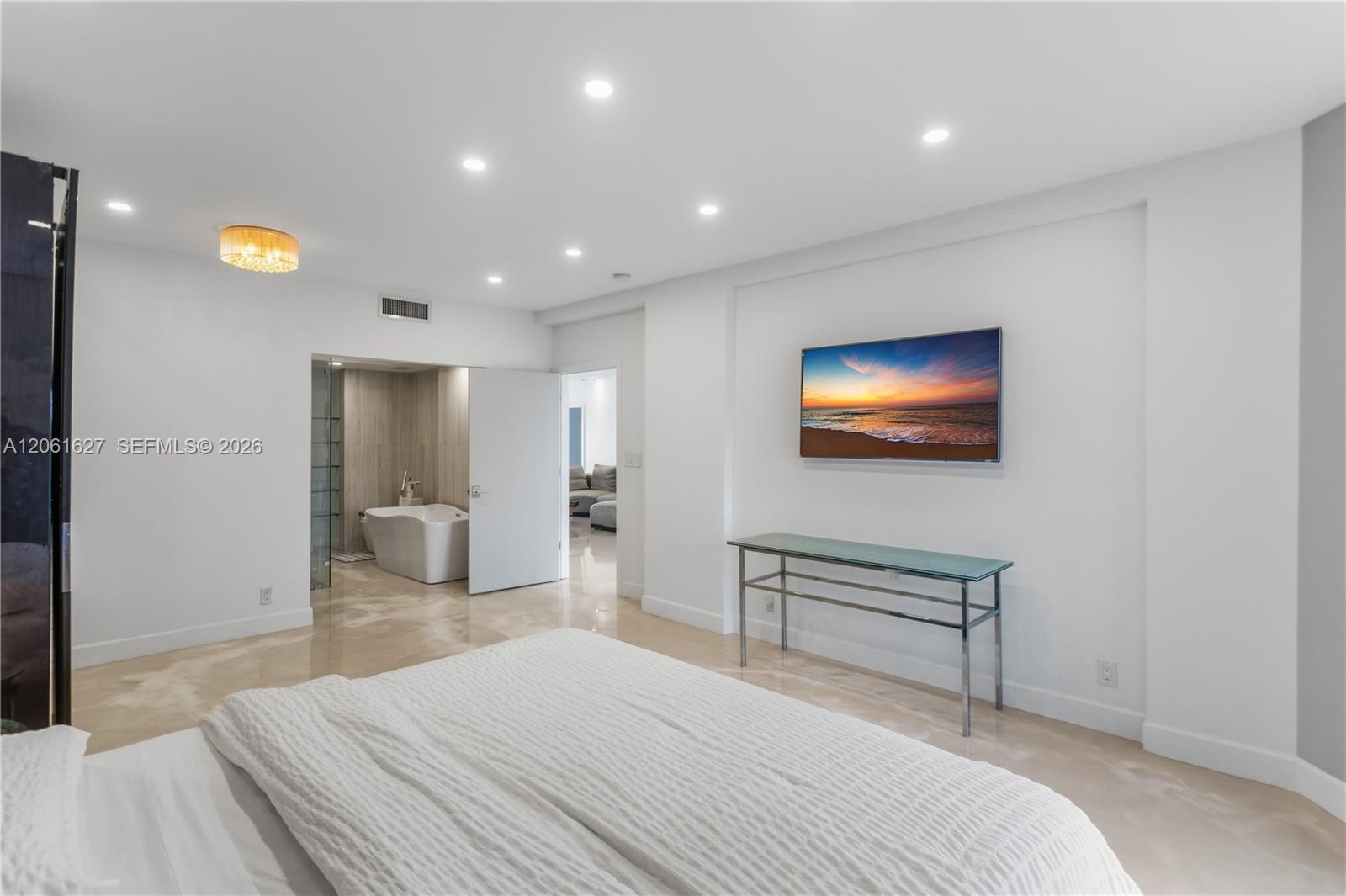 Interior room featuring recessed ceiling lighting, large-format polished stone flooring, and an integrated bathroom containing a soaking tub