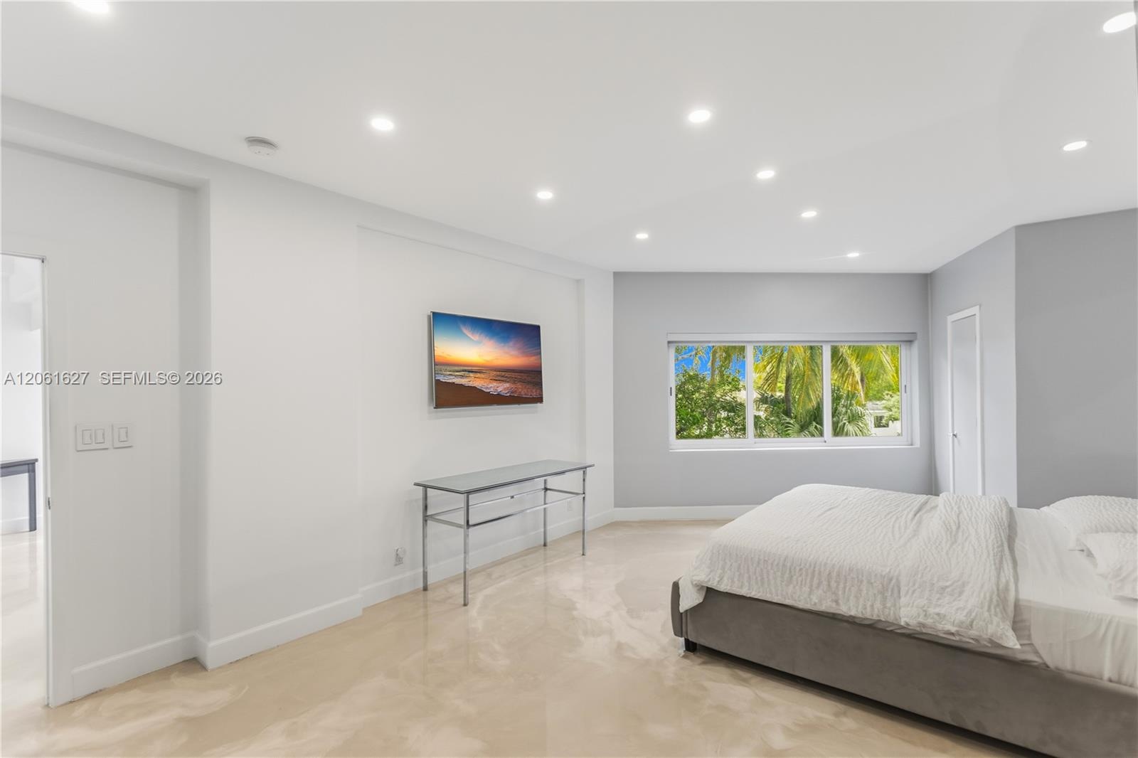 Neutral-toned interior featuring polished flooring, recessed lighting, and large windows with outdoor greenery