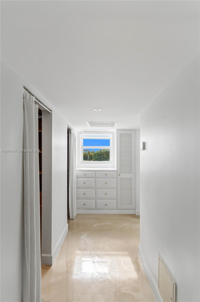 Built-in cabinetry featuring multiple drawers and a louvered door, integrated window, and polished stone-finish flooring